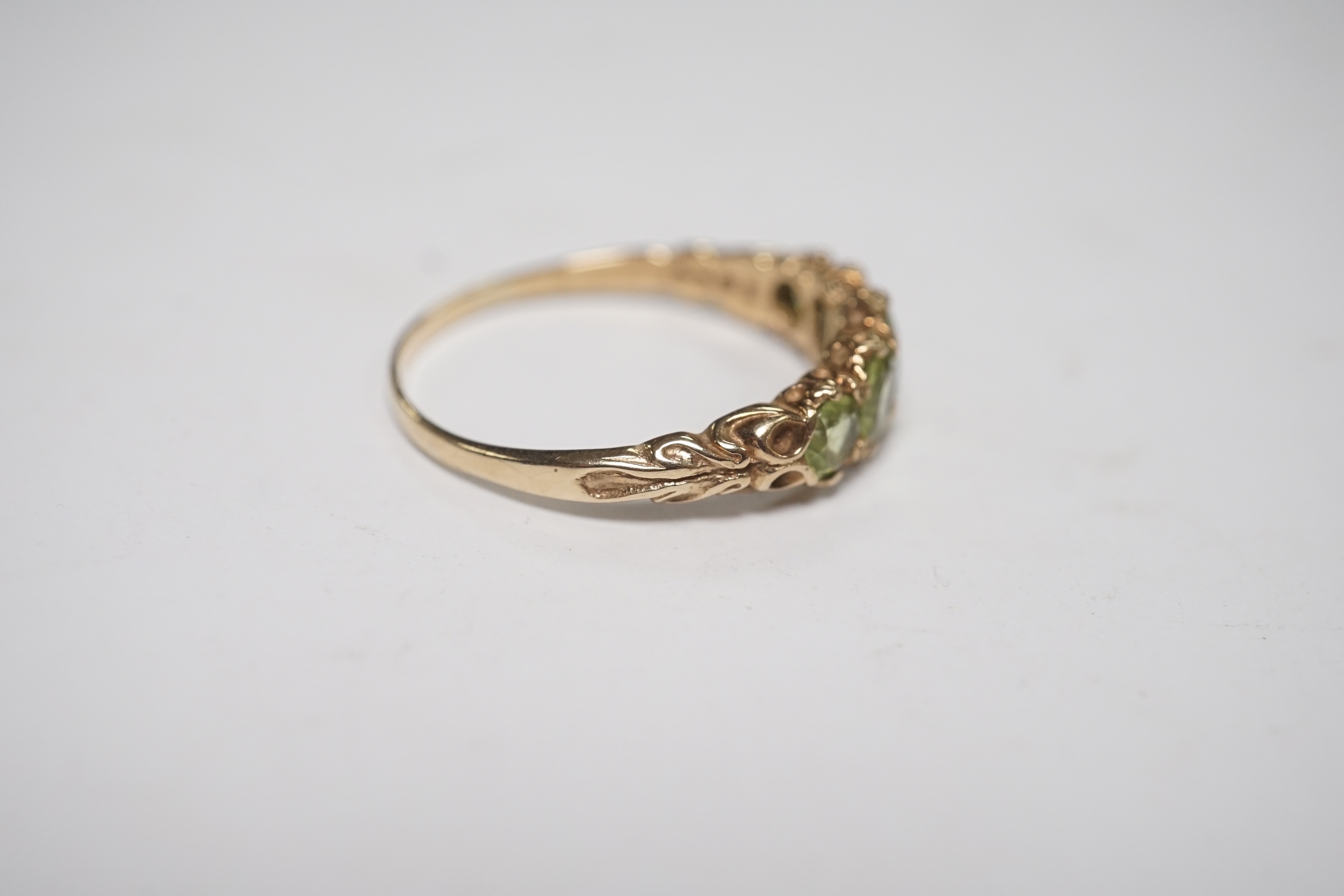 A 9ct and graduated five stone peridot set half hoop ring, size V, a 9ct gold and cameo shell ring and a gem set stickpin. Condition - poor to fair